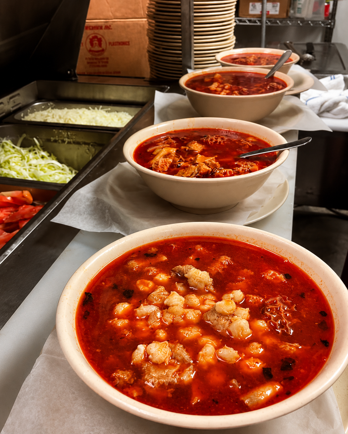 Menudo plate served with guacamole, rice, beans, pico de gallo, and salad on a white plate